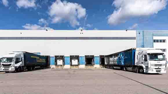 Truck bays on side of logistics warehouse with blue trim