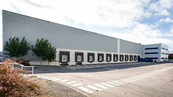 Eleven empty truck bays at logistics warehouse with two trees nearby
