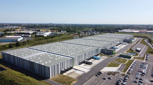 Large grey striped industrial warehouse with truck bays and multiple parking lots