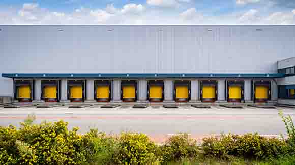 Truck bays with yellow doors on white logistics building