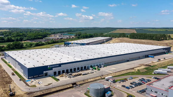 Aerial view of two large industrial warehouses with a water tower