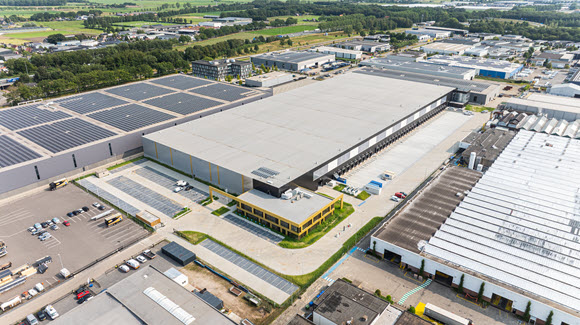 Aerial photo of large logistics park next to a building with solar panels and a large parking lot