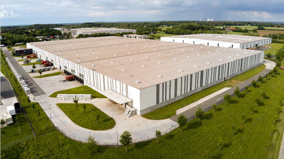 Large striped industrial warehouse with multiply buildings and truck bays fillled
