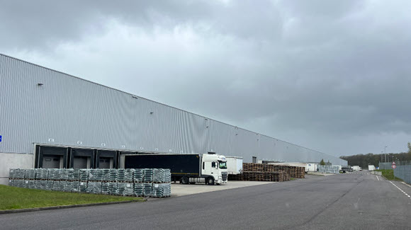 Grey industrial warehouse with large street next to truck bays