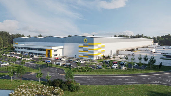 Large grey, white and yellow multi-story industrial warehouse surrounded by trees