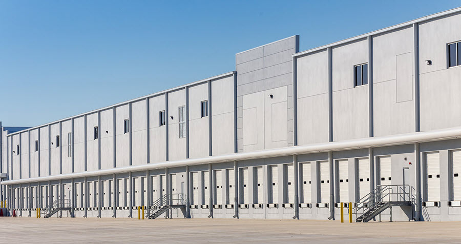 Image of grey multi-story industrial warehouse with multiple truck bays