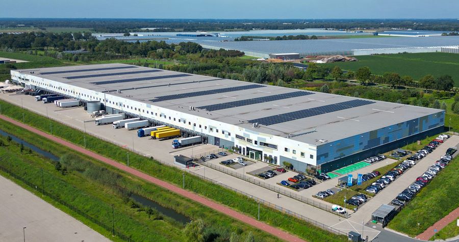 Aerial photo of large logistics warehouse with truck bays and parking