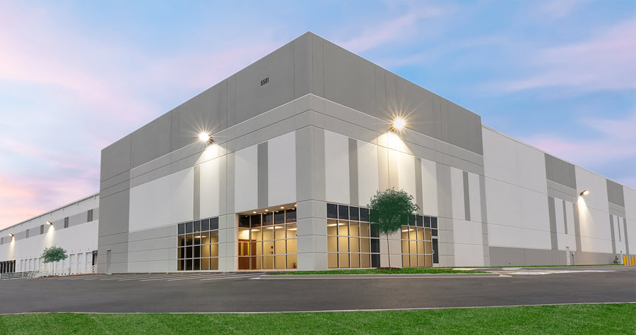 Industrial warehouse with a parking lot at sunset