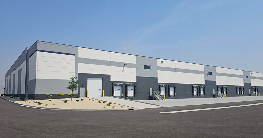 Photo of the side of a grey and white industrial building with multiple truck bays