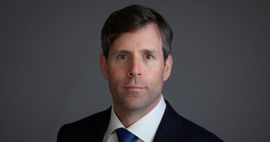 Portrait headshot of Alistair Calvert looking at the camera wearing a suit and tie