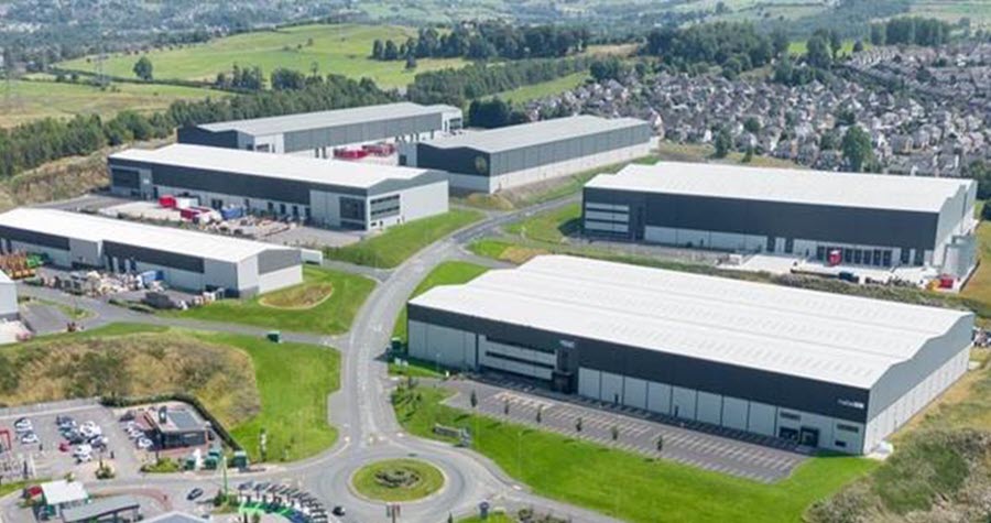 Aerial view of multi-building industrial complex near a residential town and green fields