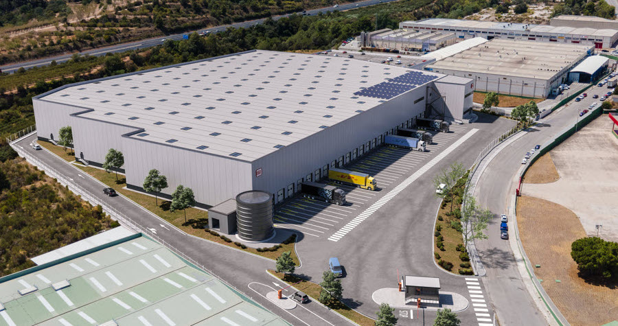Complex grey industrial buildings with a large parking lot