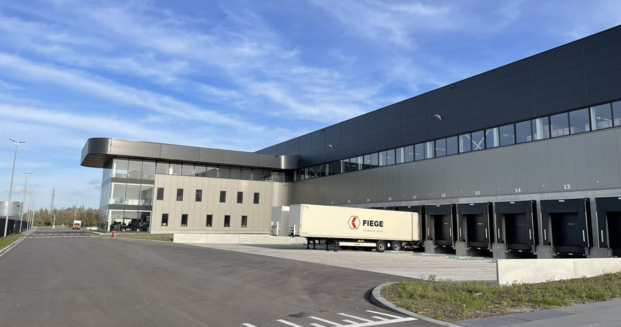 Multistory modern logistics warehouse with truck bays and Fiege trailers