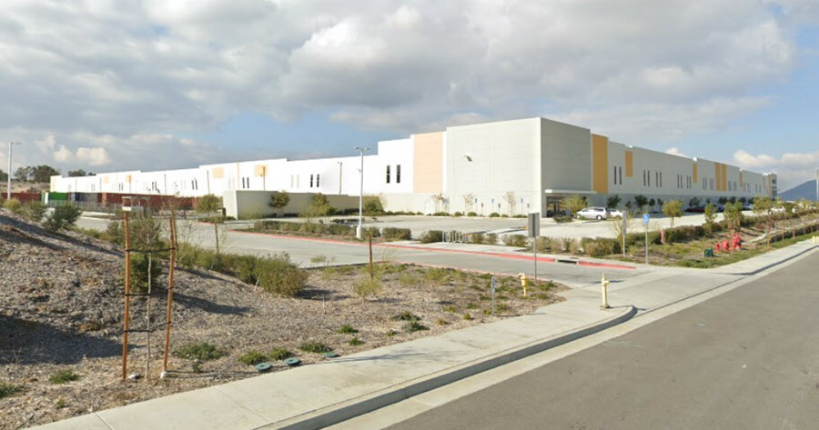 Large white and yellow industrial warehouse with parking lot