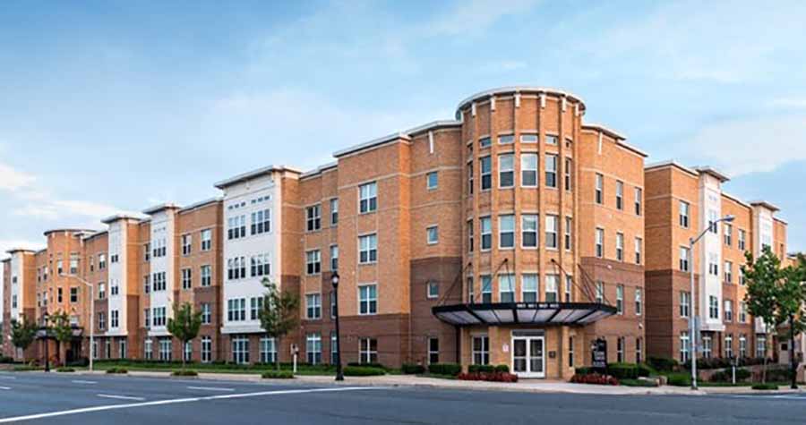 4-story light clay brick apartment building on street corner