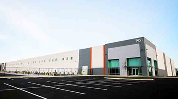 New distribution center surrounded by gleaming black parking lot and blue sky